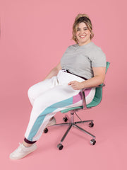 Plus size model is sitting down wearing Cece joggers sewing pattern from Tilly and the Buttons in white with colour block side panel and pockets