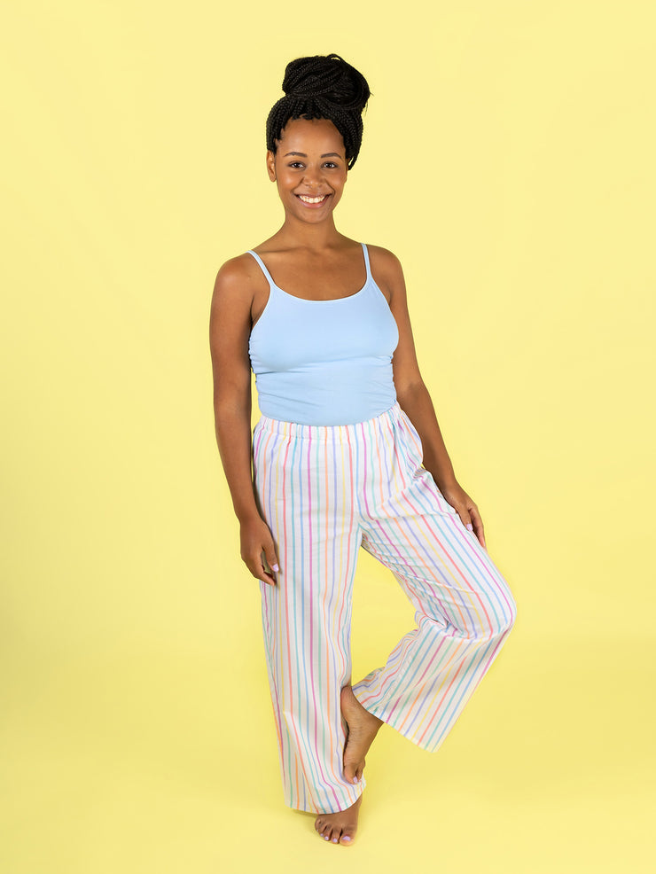 Model wearing a light blue tank top and colourful striped Jaimie pjs on a yellow background