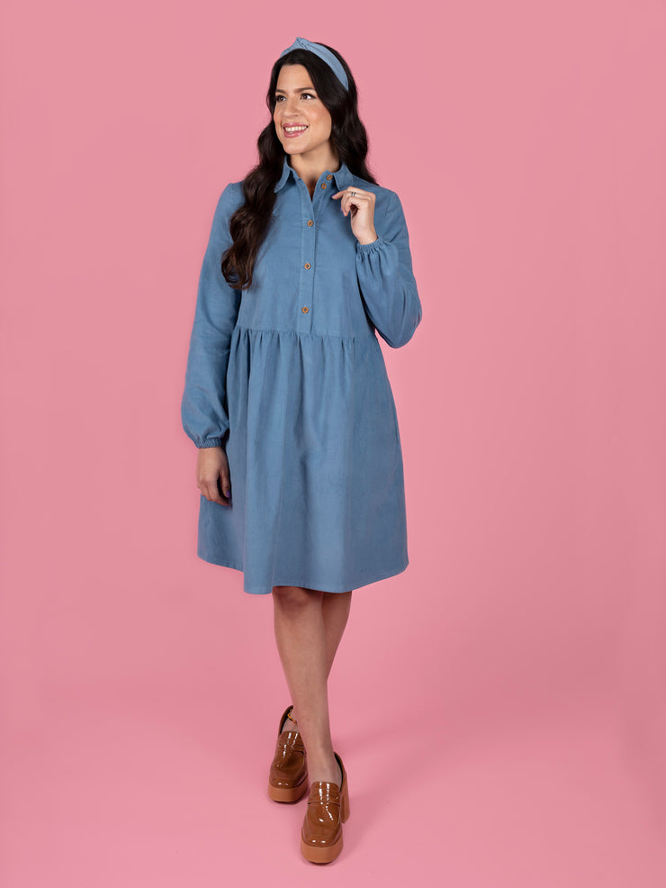 Woman wearing a blue Lyra dress on a pink background