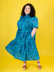 Woman wearing a blue patterned Lyra dress against a yellow background