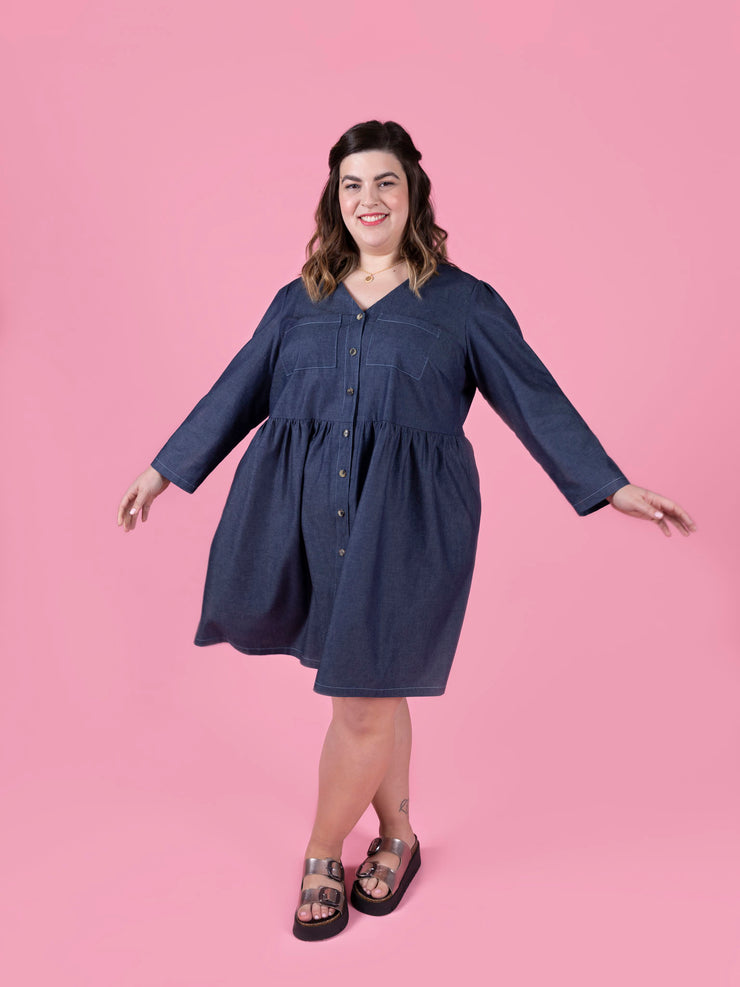 Woman wearing a blue Nell dress against a pink background