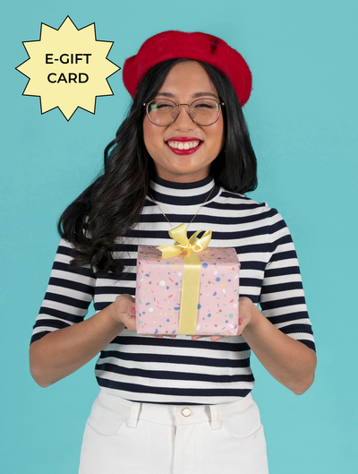 Woman holding a gift box with a red beret and striped top against a blue background