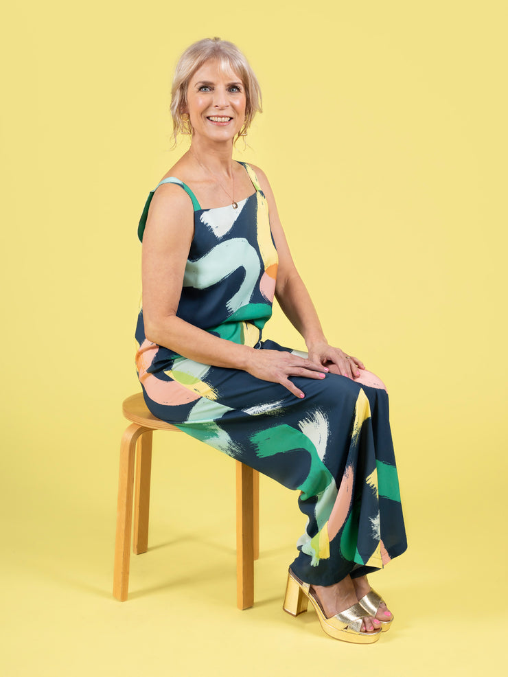 Model sitting down wearing a faux jumpsuit in a bold brushstroke print. The look was created with a matching top and trouser set, made using the Esti co-ord sewing pattern.