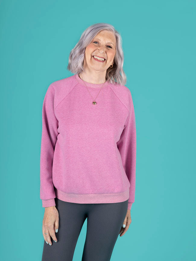 Person wearing a pink sweatshirt and gray leggings against a teal background