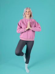Person wearing a pink sweatshirt and gray leggings on a teal background