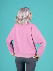 Person wearing a pink sweater against a teal background