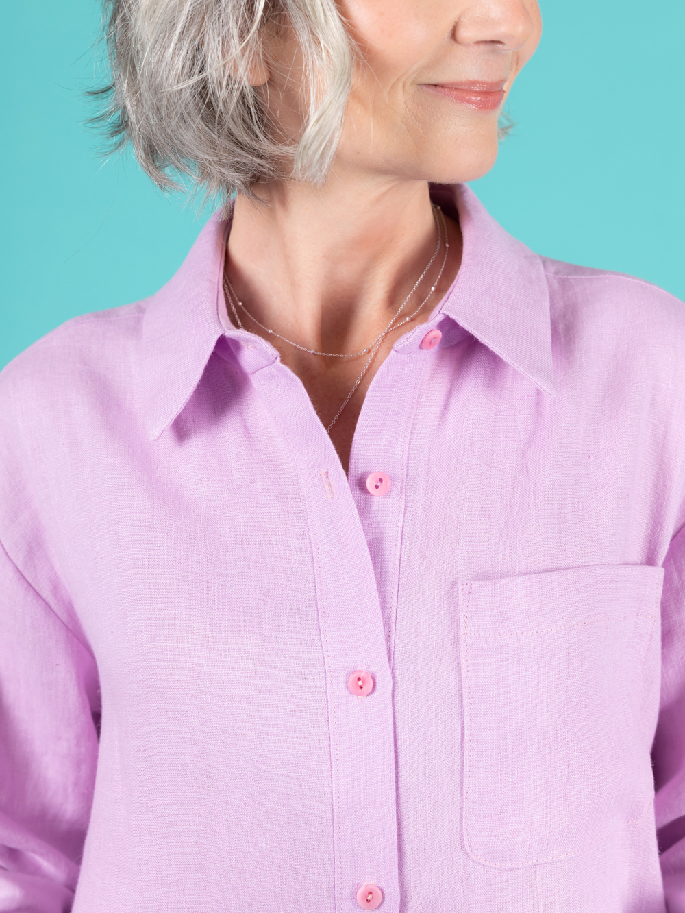 Close up of the collar of a lilac Frida shirt against a teal background.