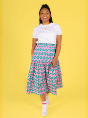 Model wearing a white t-shirt and a pink Luella skirt on a yellow background