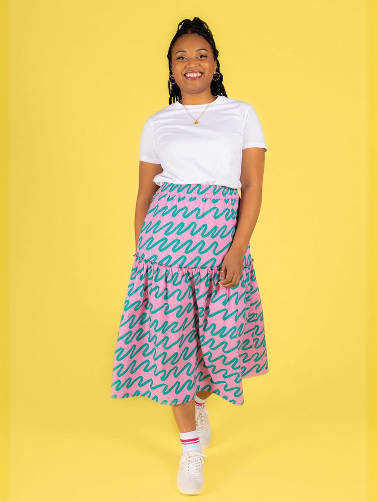 Model wearing a white t-shirt and a pink Luella skirt on a yellow background