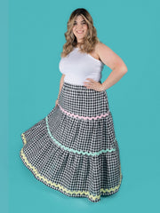 Model wearing a gingham Luella skirt with colourful trim on a teal background