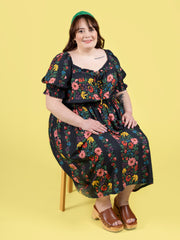 Plus size model sitting wearing a floral shirred dress, made using Tilly and the Buttons Mabel sewing pattern