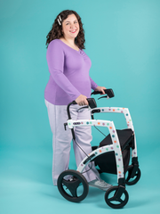 Model with brunette curly hair holding mobility aid walker wears purple long sleeve jersey top with sweetheart neckline