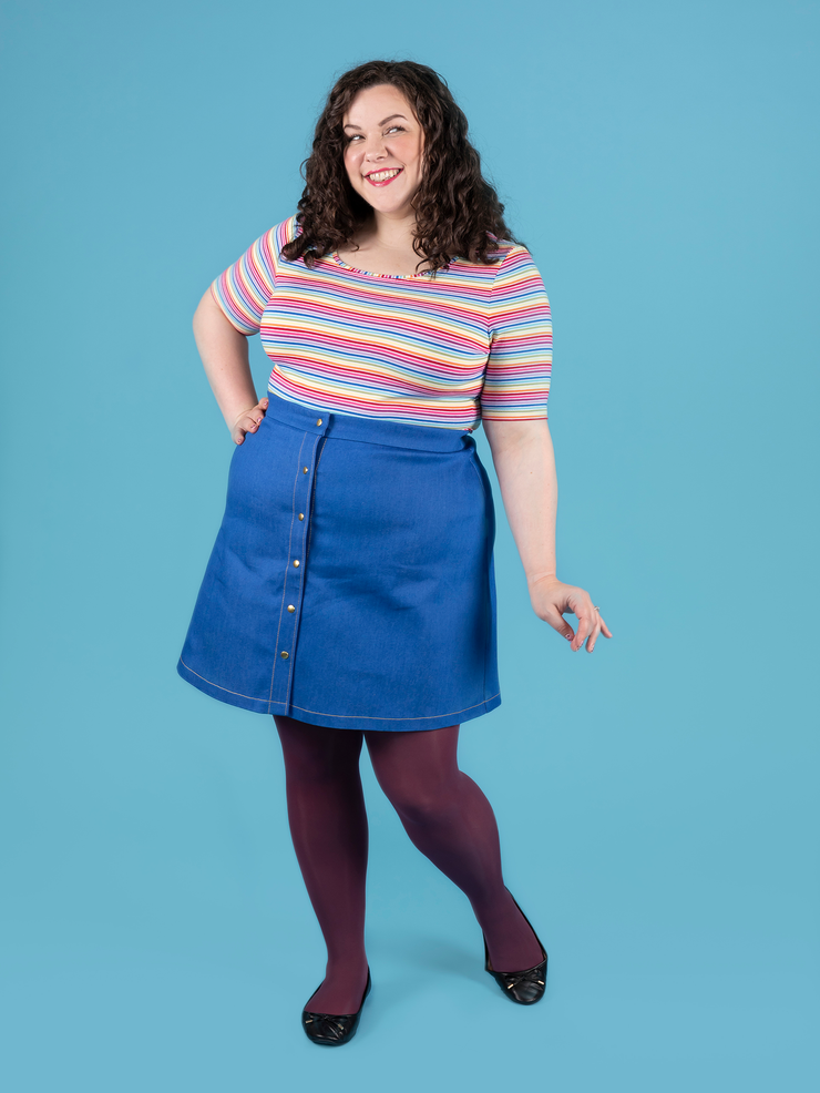 Model with curly brunette hair wears short sleeve rainbow stripe Agnes top