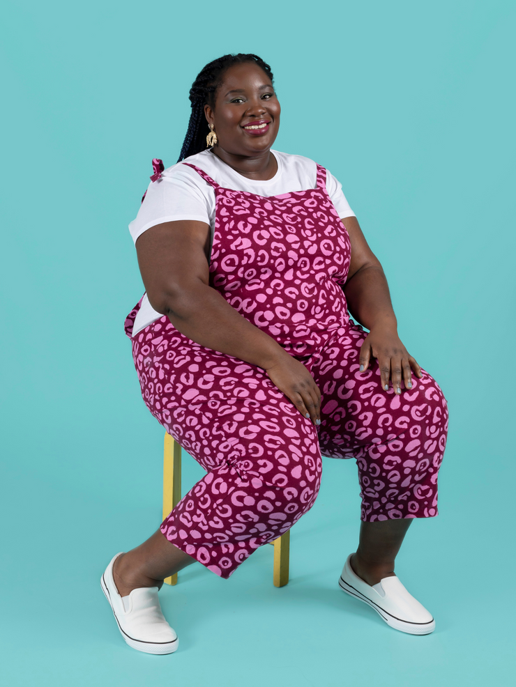 Curvy, plus size model sitting while wearing long dungarees or overalls handmade using the Erin sewing pattern