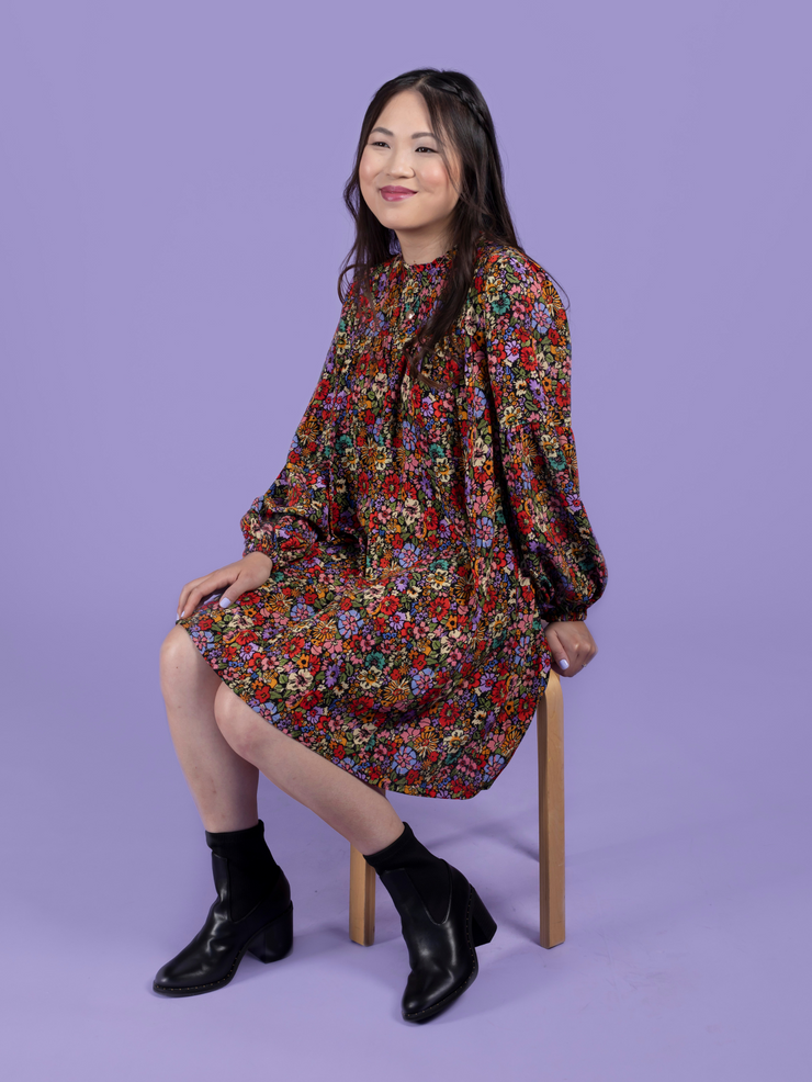 Model sitting down wearing a floral mini dress, made using the Marnie sewing pattern in viscose crepe.