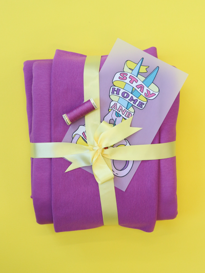 Contents of Tilly and the Buttons' Billie sweatshirt kits - fabric, thread and a 'stay home and sew' iron-on transfer, in orchid colour, tied with yellow ribbon.